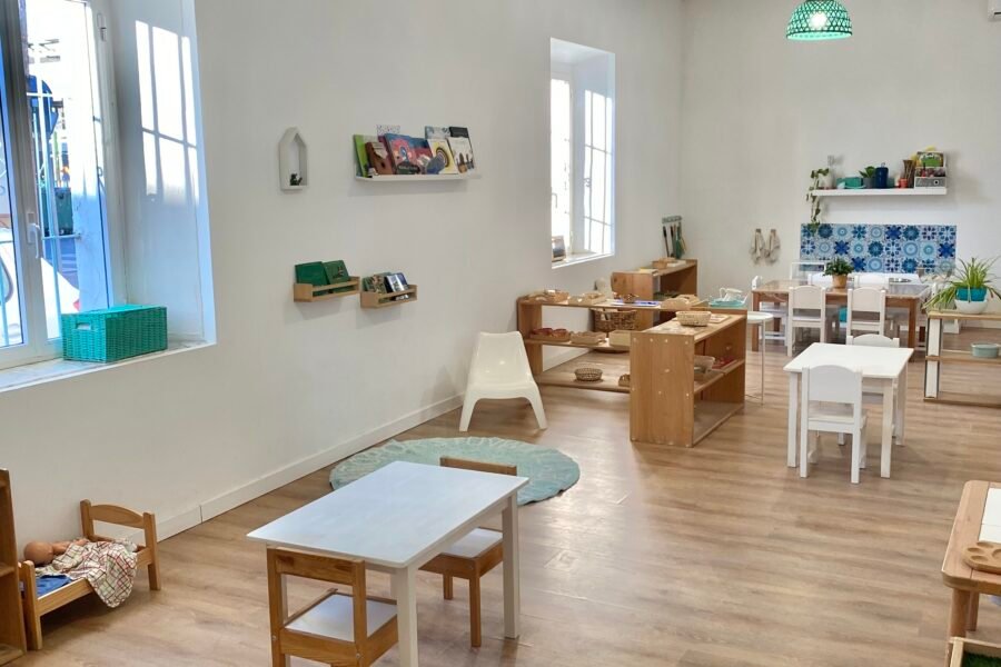 Ambiente de Comunidad Infantil luminoso con mesas pequeñas, plantas y luz natural